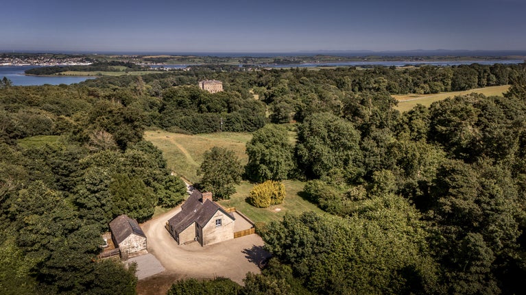 An aerial view of Castle Ward Gamekeeper's Lodge, with Castle Ward mansion and Strangford Lough in the background, County Down